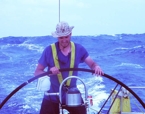 Author / Photographer Ed Darack at the helm of an Andrews 70 racing yacht during a lull in a storm in the South China Sea while on a 2,000 mile sailing trip from Hong Kong, up the Strait of Malacca, to Malaysia, during which he conducted research for his forthcoming novel series. Copyright Ed Darack; Permission granted for use in media products about / related to Ed Darack's creative work. width=